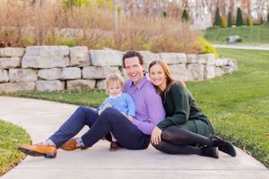 Family relaxing together on stone ledge during outdoor photo session in Springfield, MO.