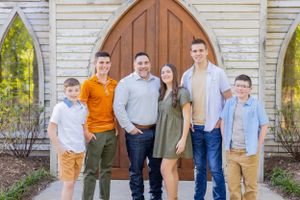 Family group portrait in front of white chapel with wooden door in Springfield, MO.