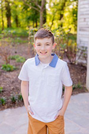 Young person in white polo and orange pants poses in front of chapel in Springfield, MO.