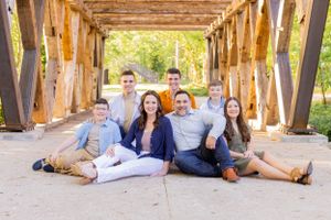 Group poses casually together on wooden bridge structure during outdoor photo session in Springfield, MO.
