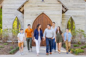 Family group walking together in front of white chapel with arched wooden door in Springfield, MO.