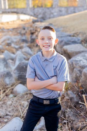 Young person in light blue polo shirt poses outdoors among rocky terrain in Springfield, MO.