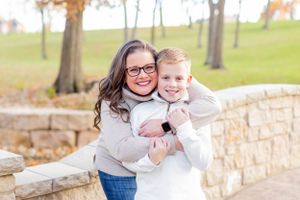 Two people share a warm embrace while standing by a stone wall during fall season in Springfield, MO.