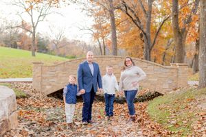 A family walks together among fallen leaves on a stone path during autumn in Springfield, MO.