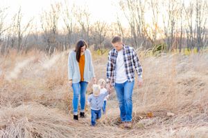 A family walks together through tall prairie grass during golden hou in Springfield, MO.