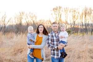 A family of four poses together in a field of tall grass during sunset in Springfield, MO.