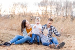 A family sits together in a field of tall golden grass at sunset in Springfield, MO.