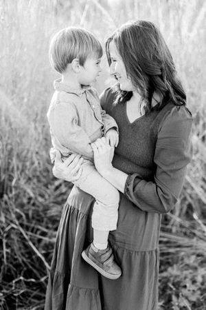 A black and white portrait showing a tender moment between two people in tall grass in Springfield, MO.