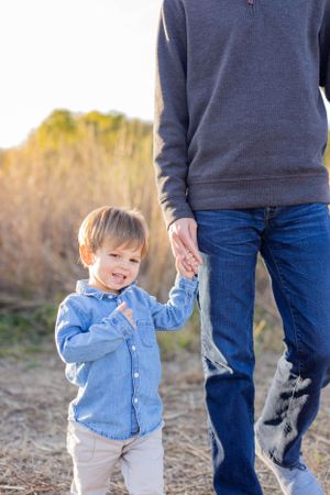 Small child in blue shirt holding hands with parent while walking outdoors in Springfield, MO..