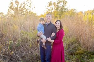 Family portrait outdoors with tall grass and golden sunlight in background in Springfield, MO..