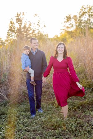 Family walking together through field with tall grass at sunset in Springfield, MO.