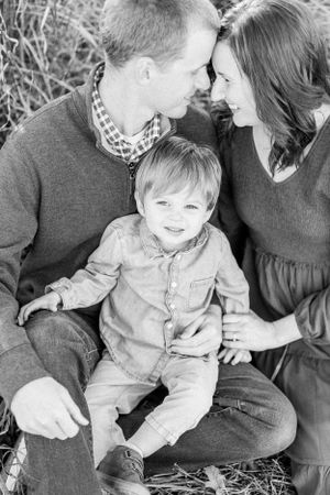 A black and white portrait of a family sharing an intimate moment in tall grass in Springfield, MO.