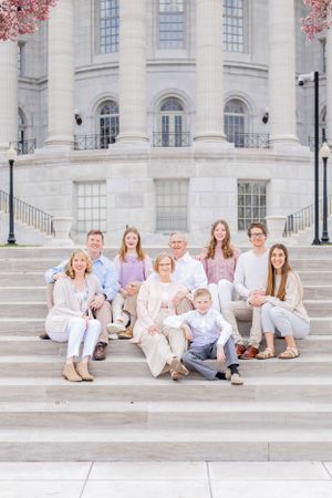 Multi-generational family poses for portrait on grand stone steps of historic building.