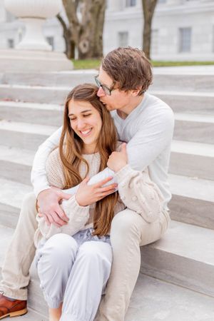 Couple shares intimate moment while sitting together on stone steps outdoors.
