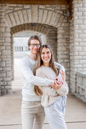Couple in casual wear embracing under stone archway in Springfield, MO.