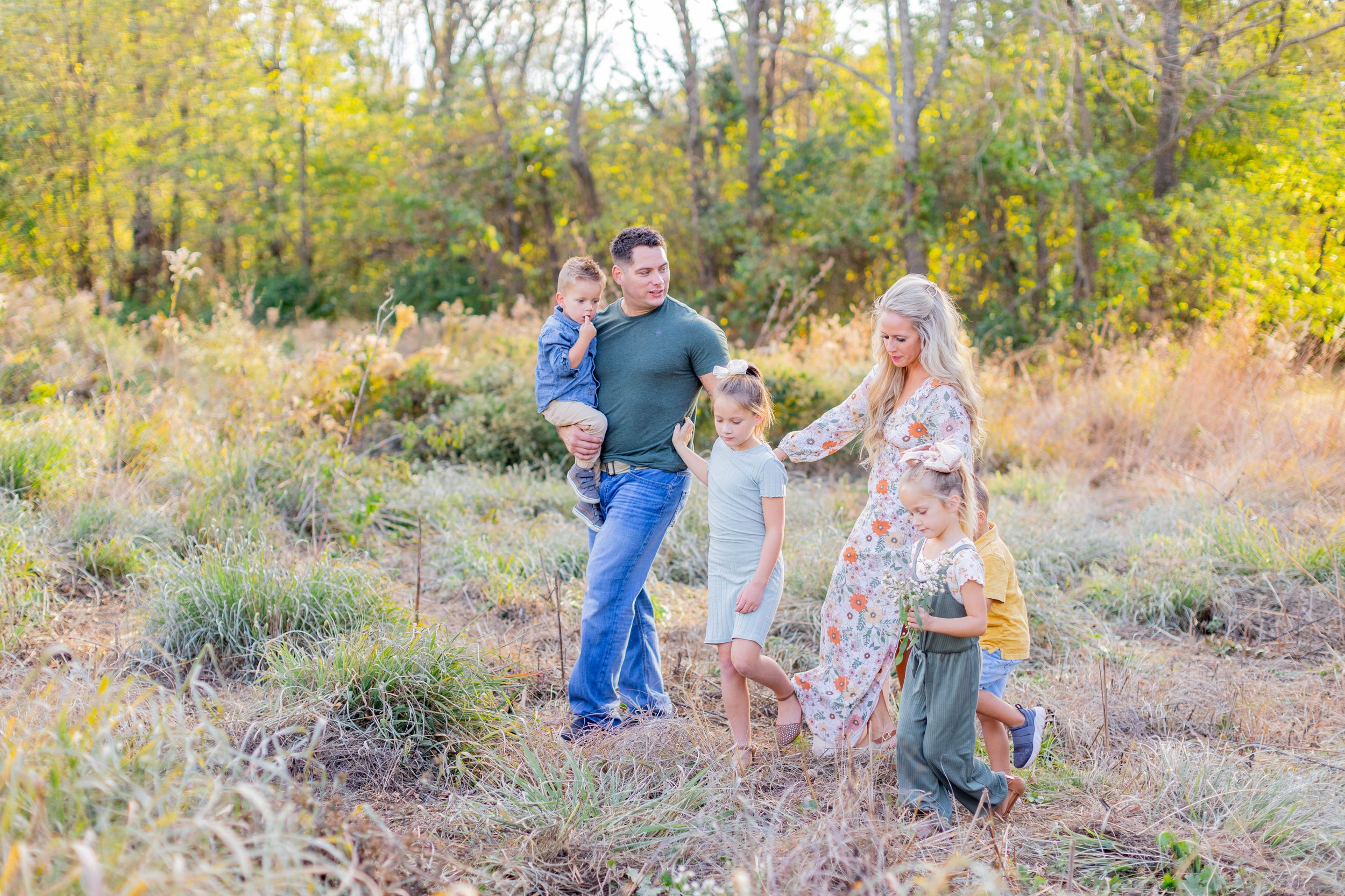 A family enjoys a playful moment together in a golden autumn field during sunset in Springfield, MO.