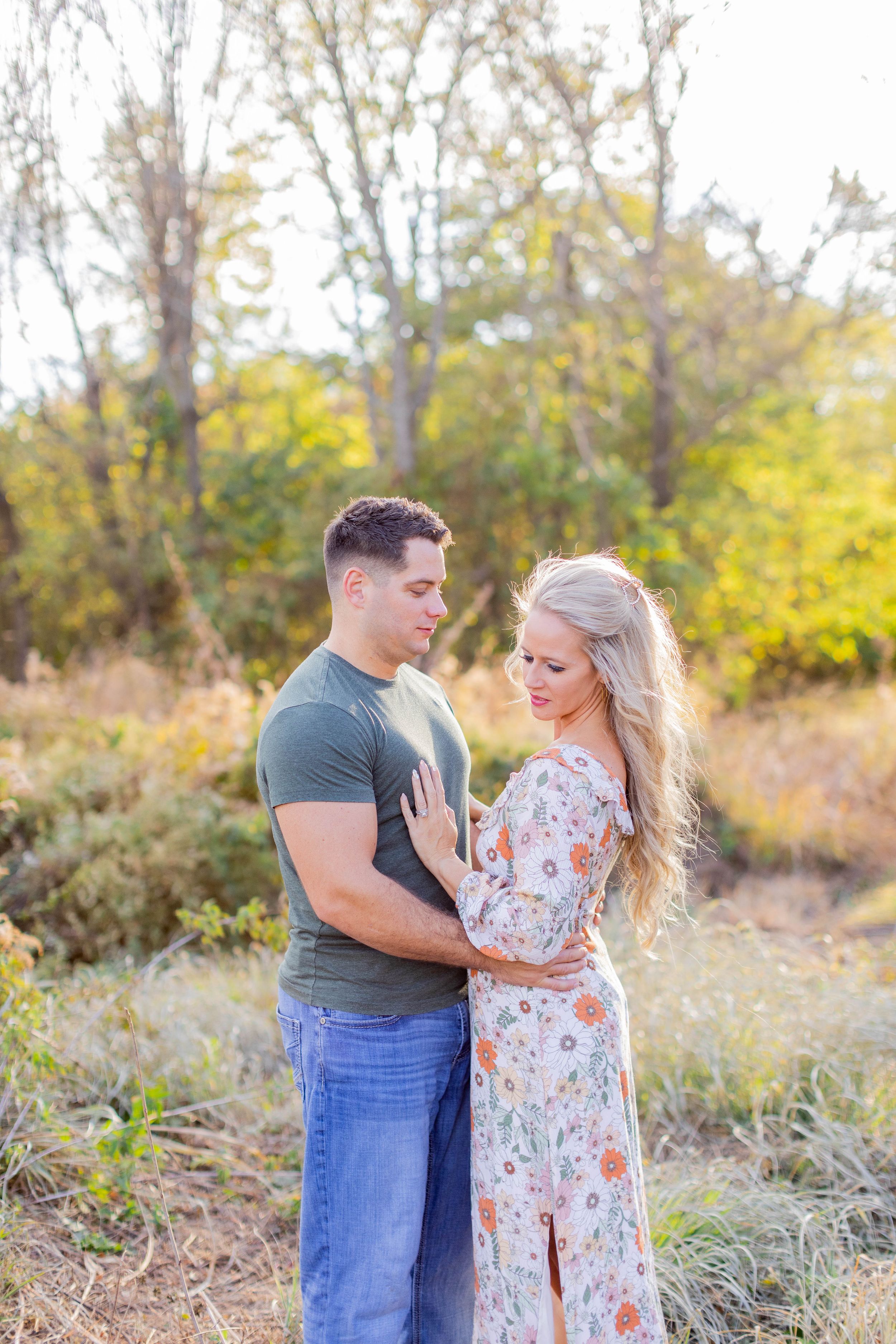 Couple embraces in romantic pose against autumn foliage background in Springfield, MO.