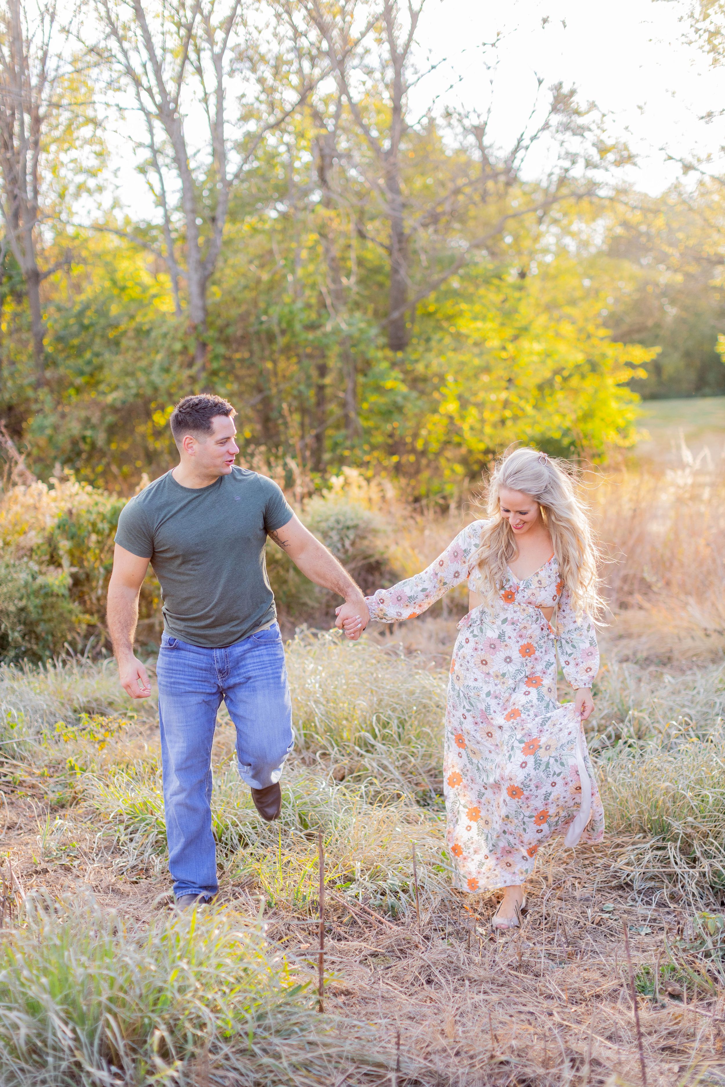 A couple walks hand in hand through tall grass during golden hour in Springfield, MO.
