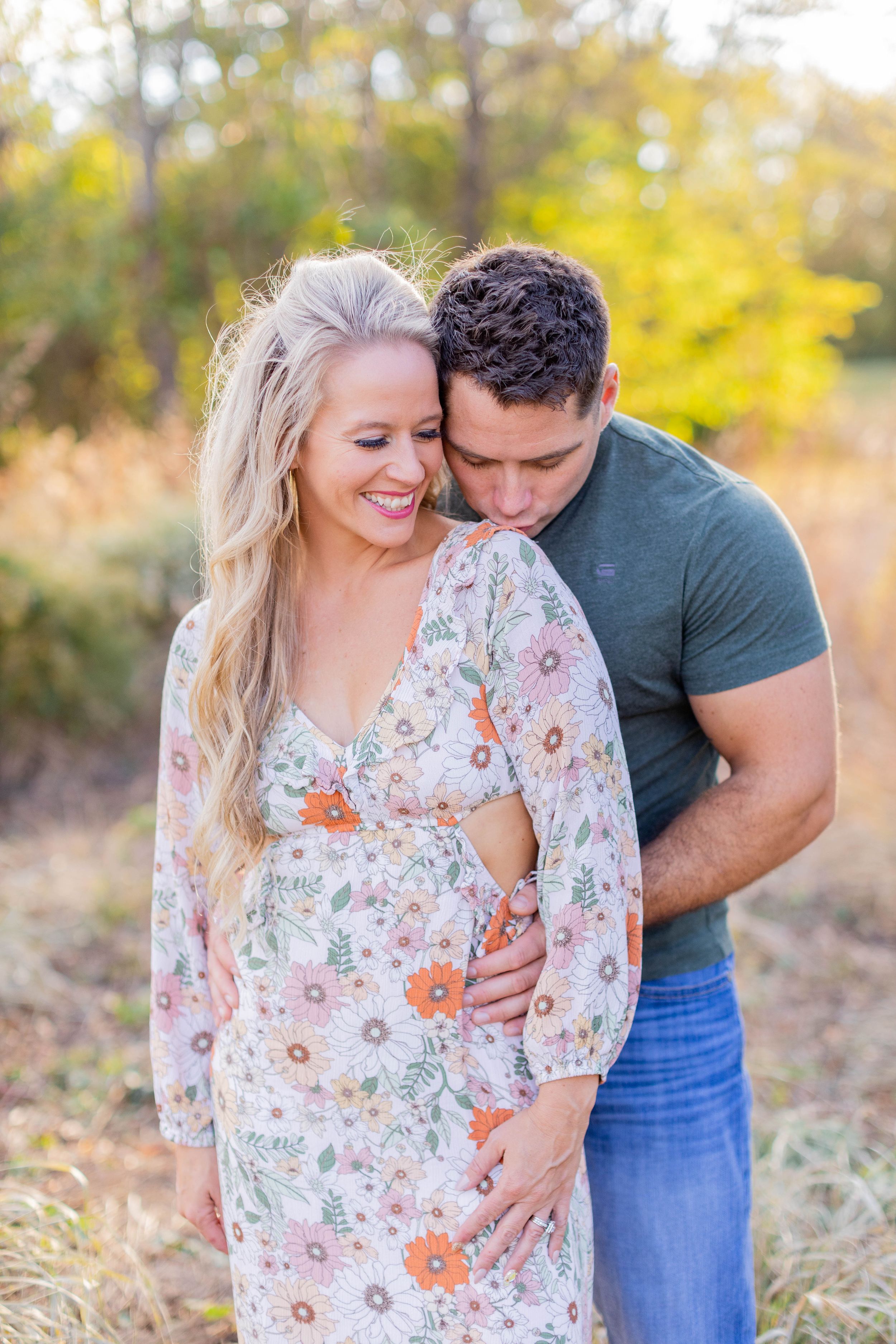 A couple shares an intimate moment in a floral dress and casual attire outdoors in Springfield, MO.