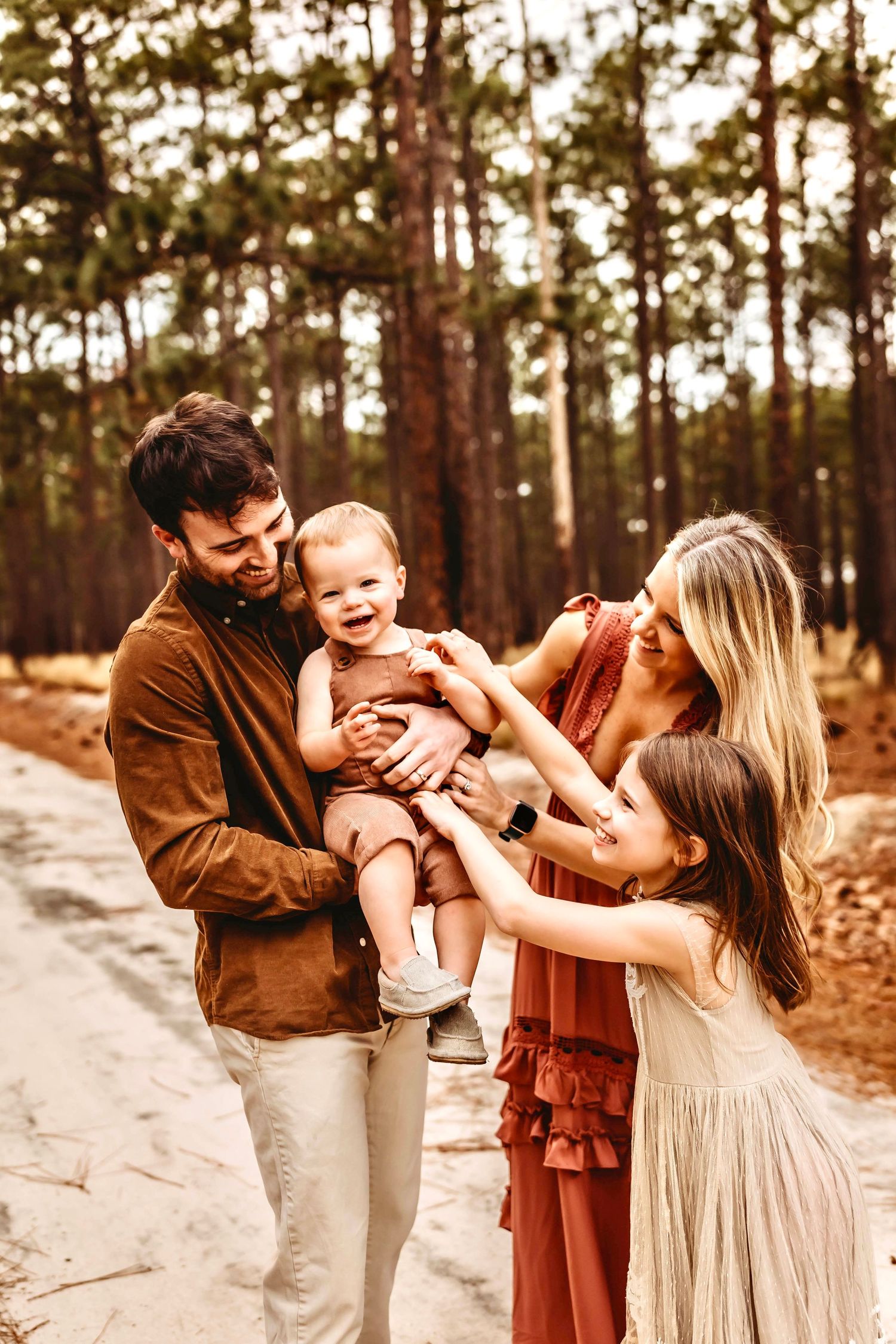 Laughing family tickles happy baby in family session in forest in Connecticut