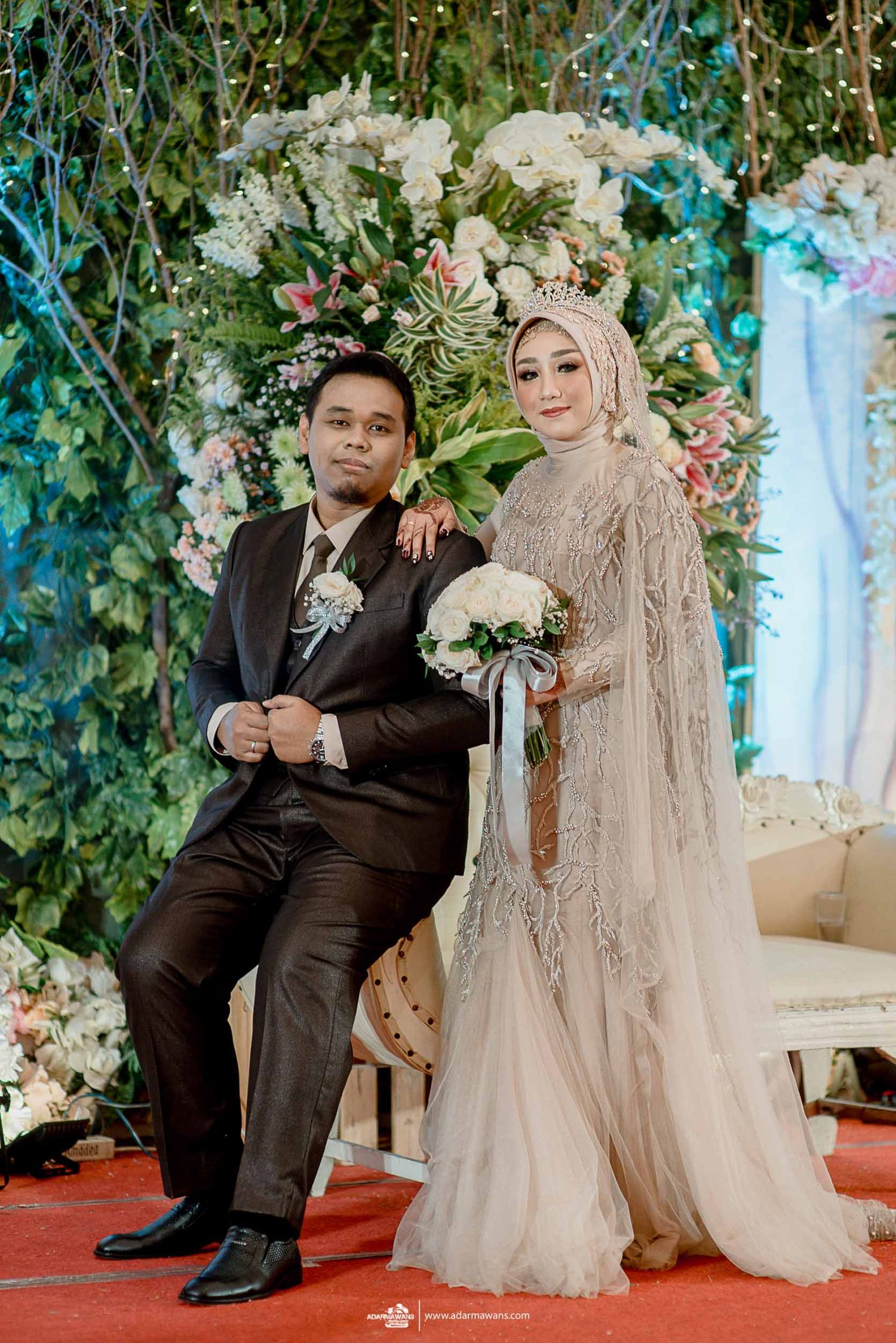 Traditional Indonesian wedding ceremony setup with lush floral backdrop and elegant decor.
