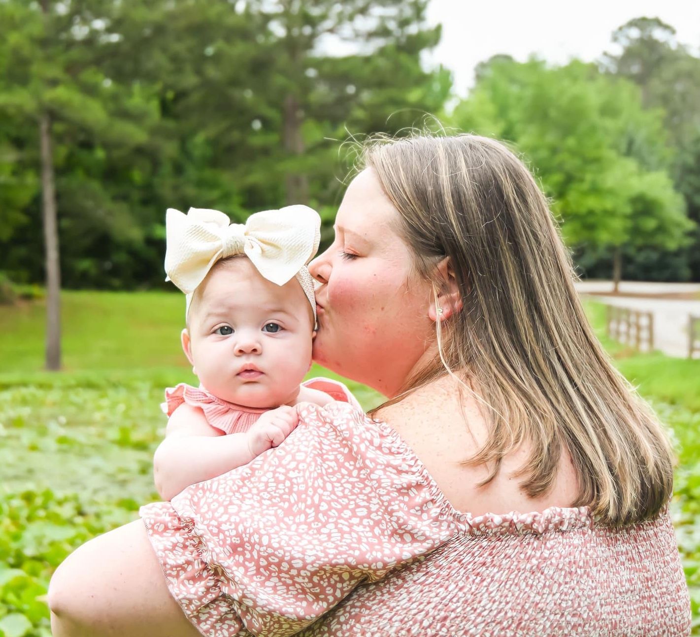 Mother and baby in matching pink outfits share tender moments outdoors in spring.