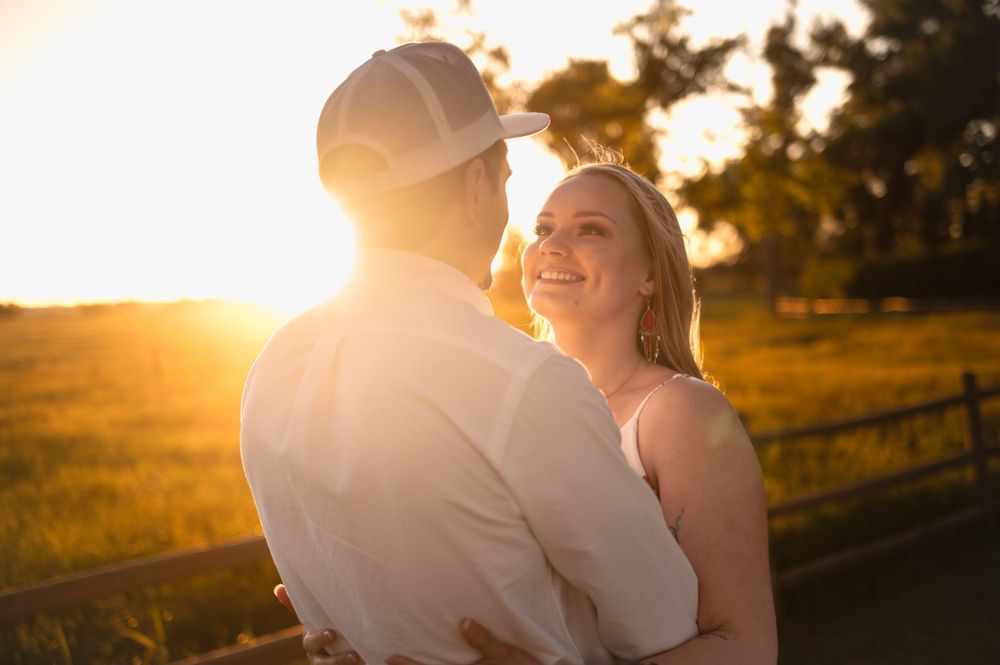 A romantic sunset moment captured as a couple embraces in a rural setting.