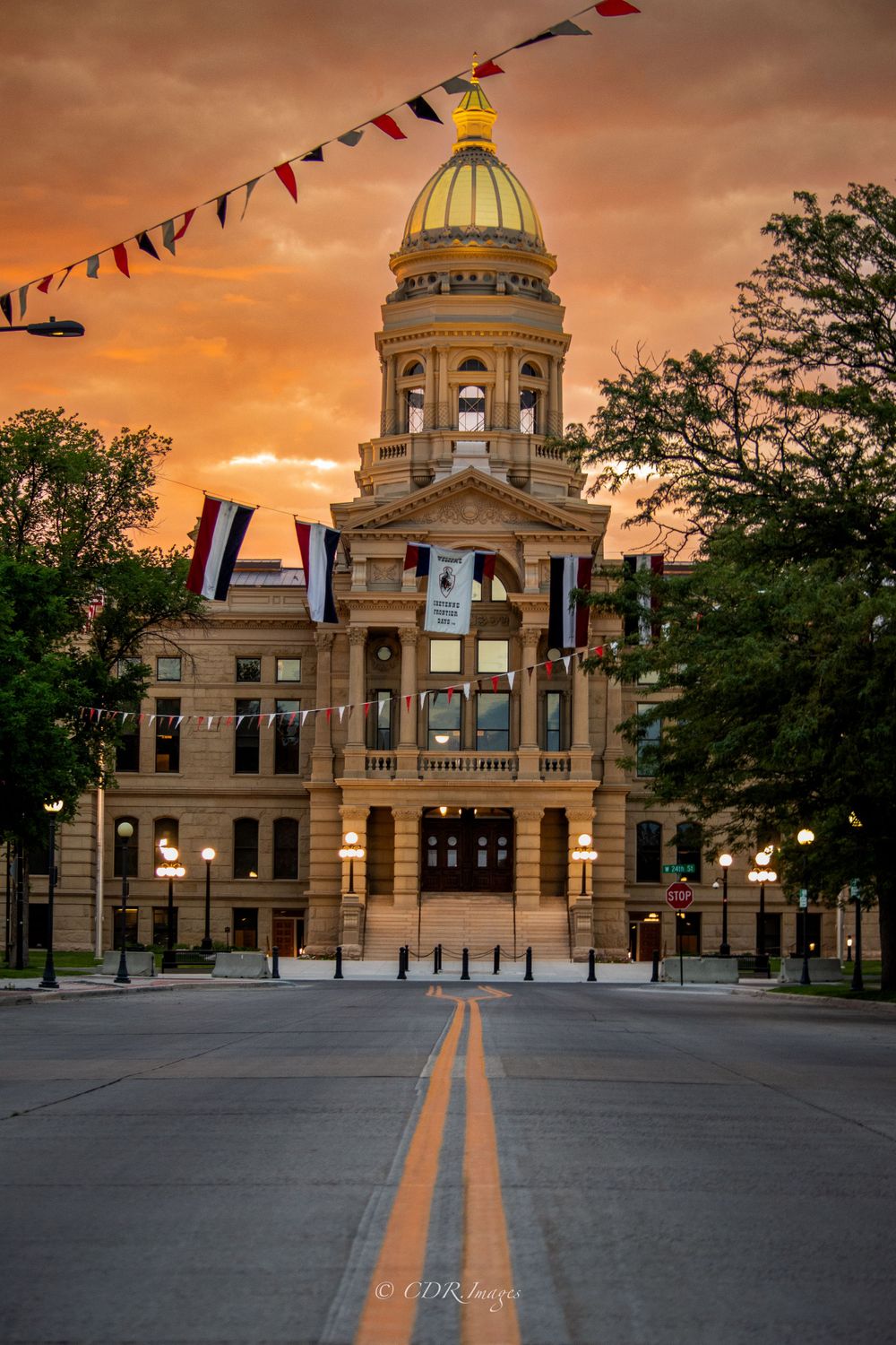 Historic courthouse building with golden dome captured at sunset with colorful bunting overhead.