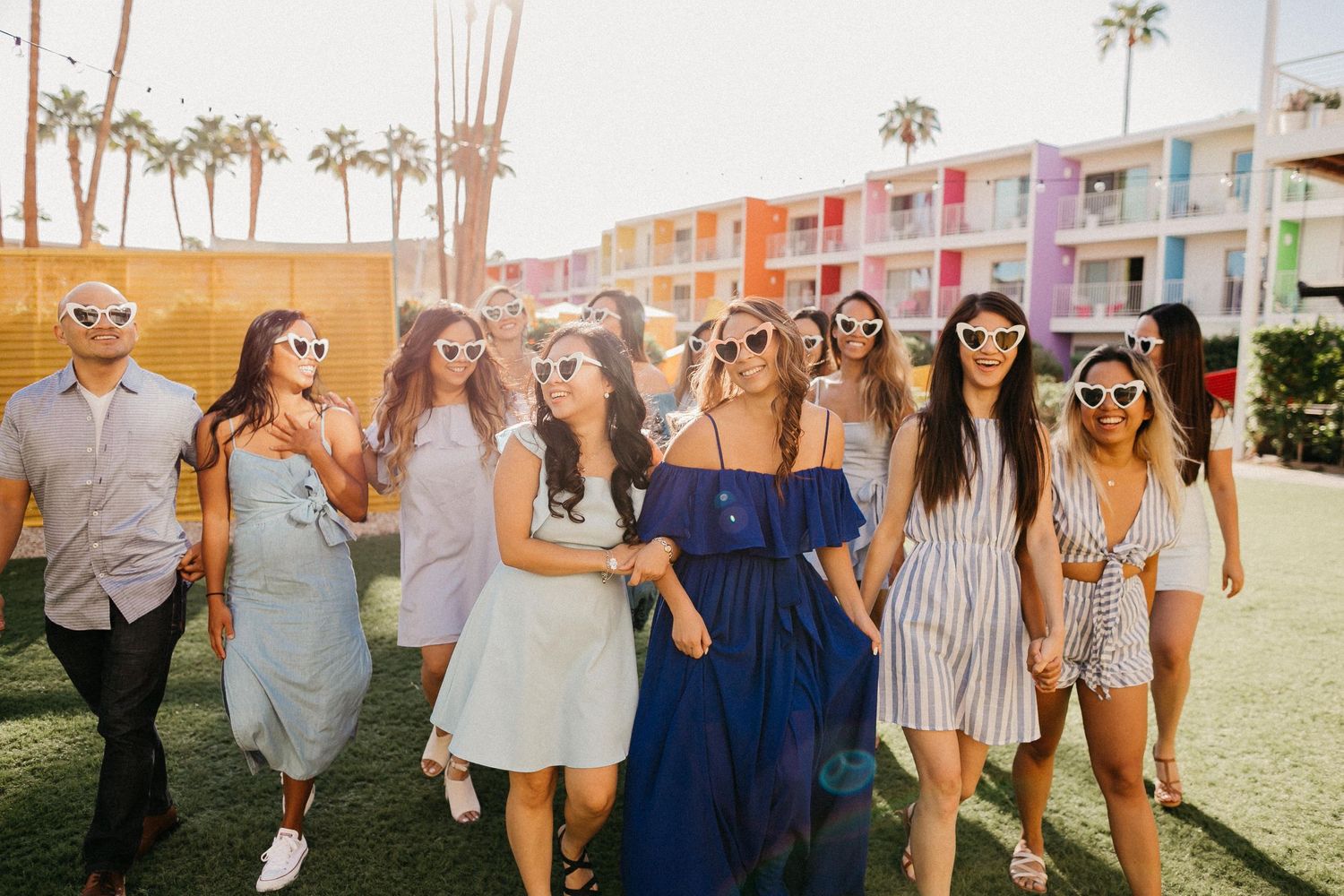 Group walking together at colorful retro motel with palm trees.