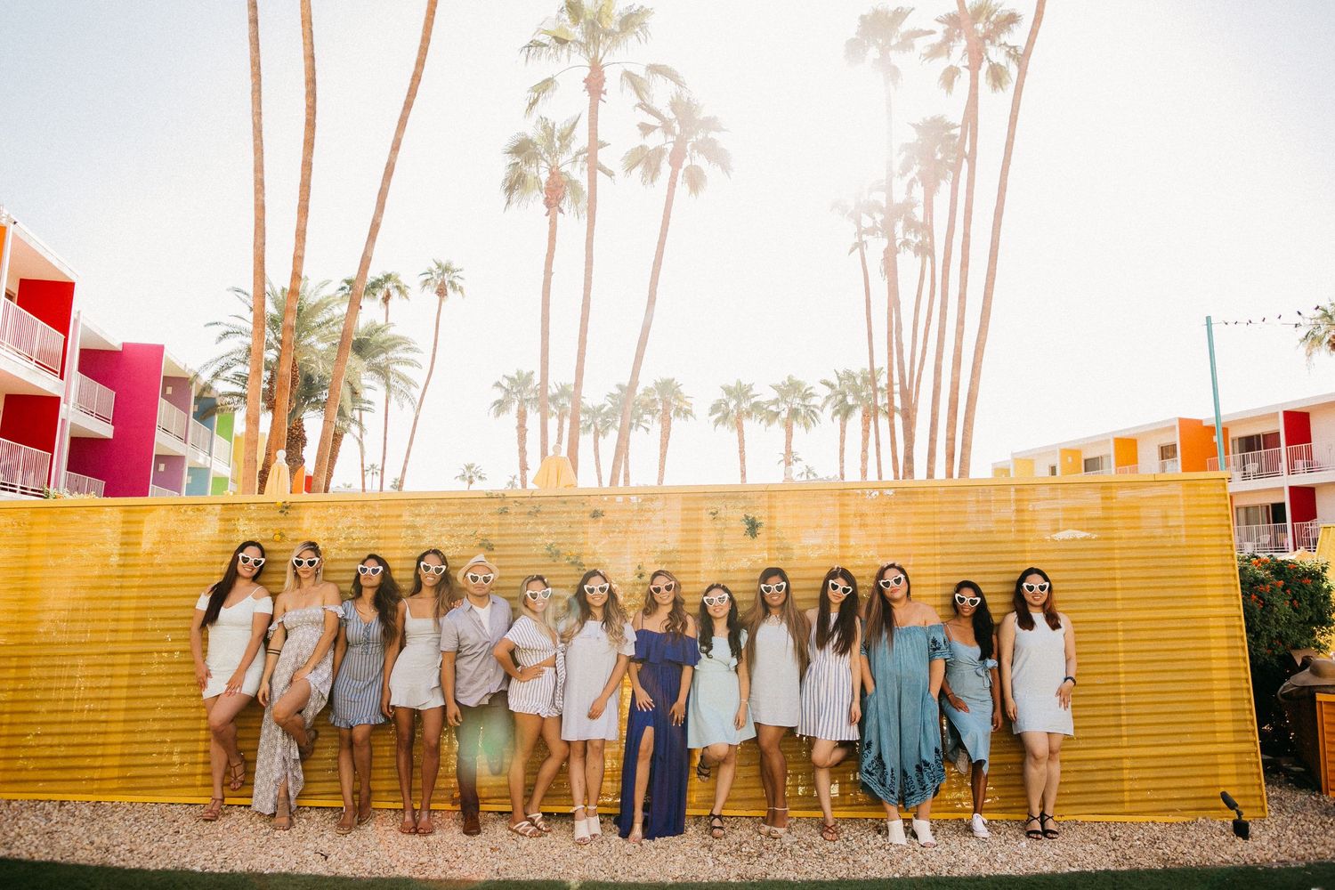 A group poses on yellow steps against a palm tree backdrop.