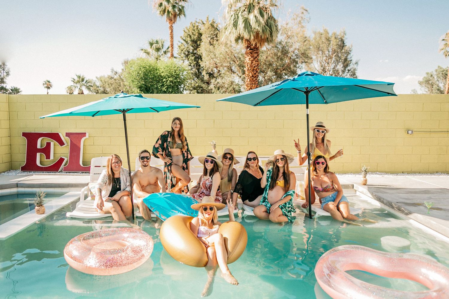 A festive pool party with colorful floats and turquoise umbrellas.