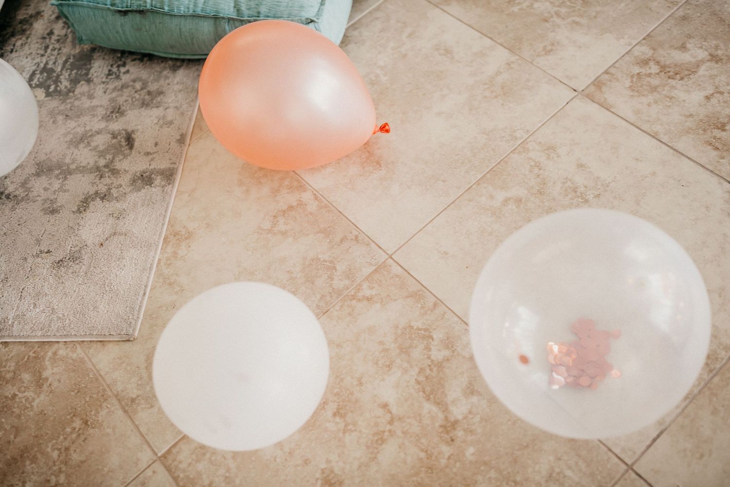 Pink and white balloons scattered on a tiled floor.