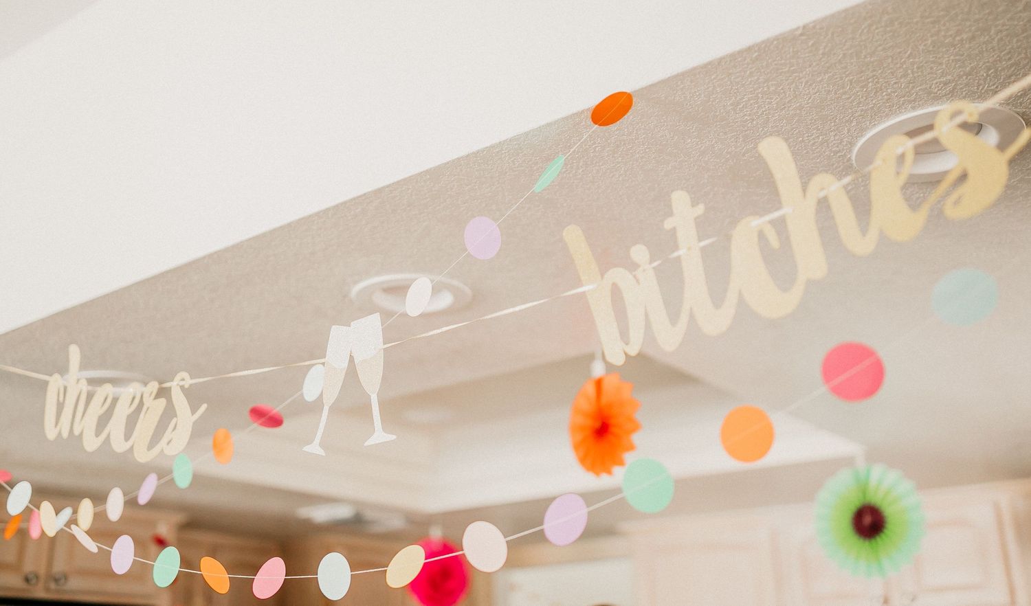 Decorative text and colorful dot garland hanging on a wall.