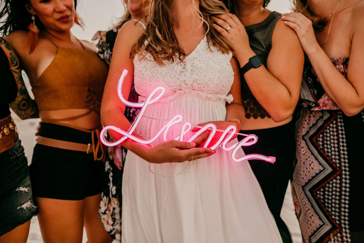 Pink neon 'Love' sign held during celebration.