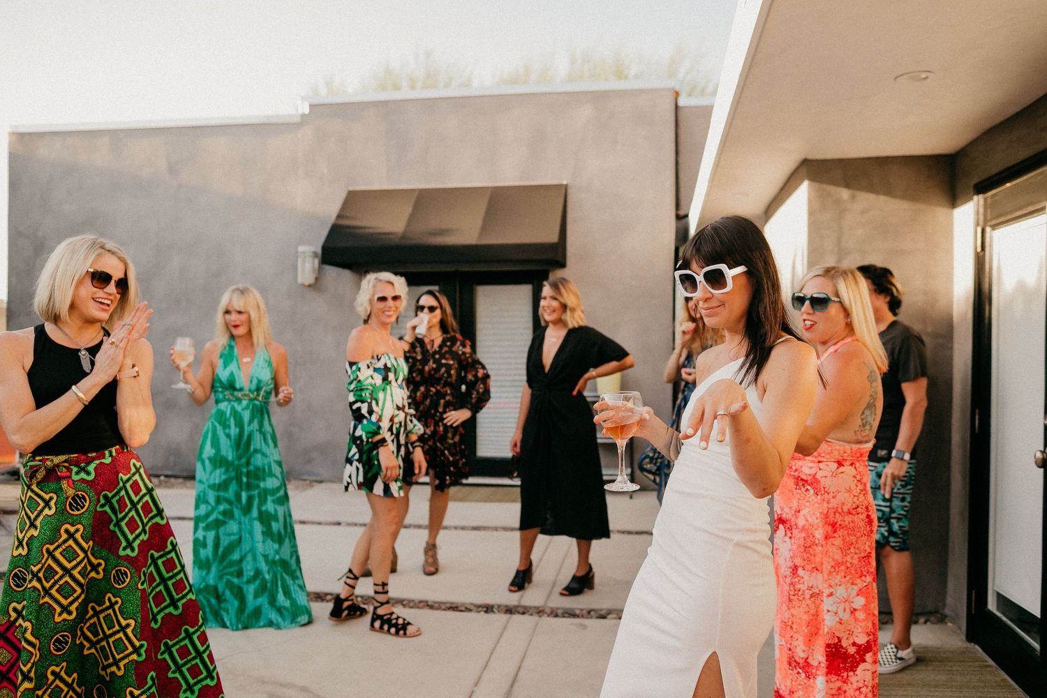 Group gathering on modern patio in colorful summer dresses.