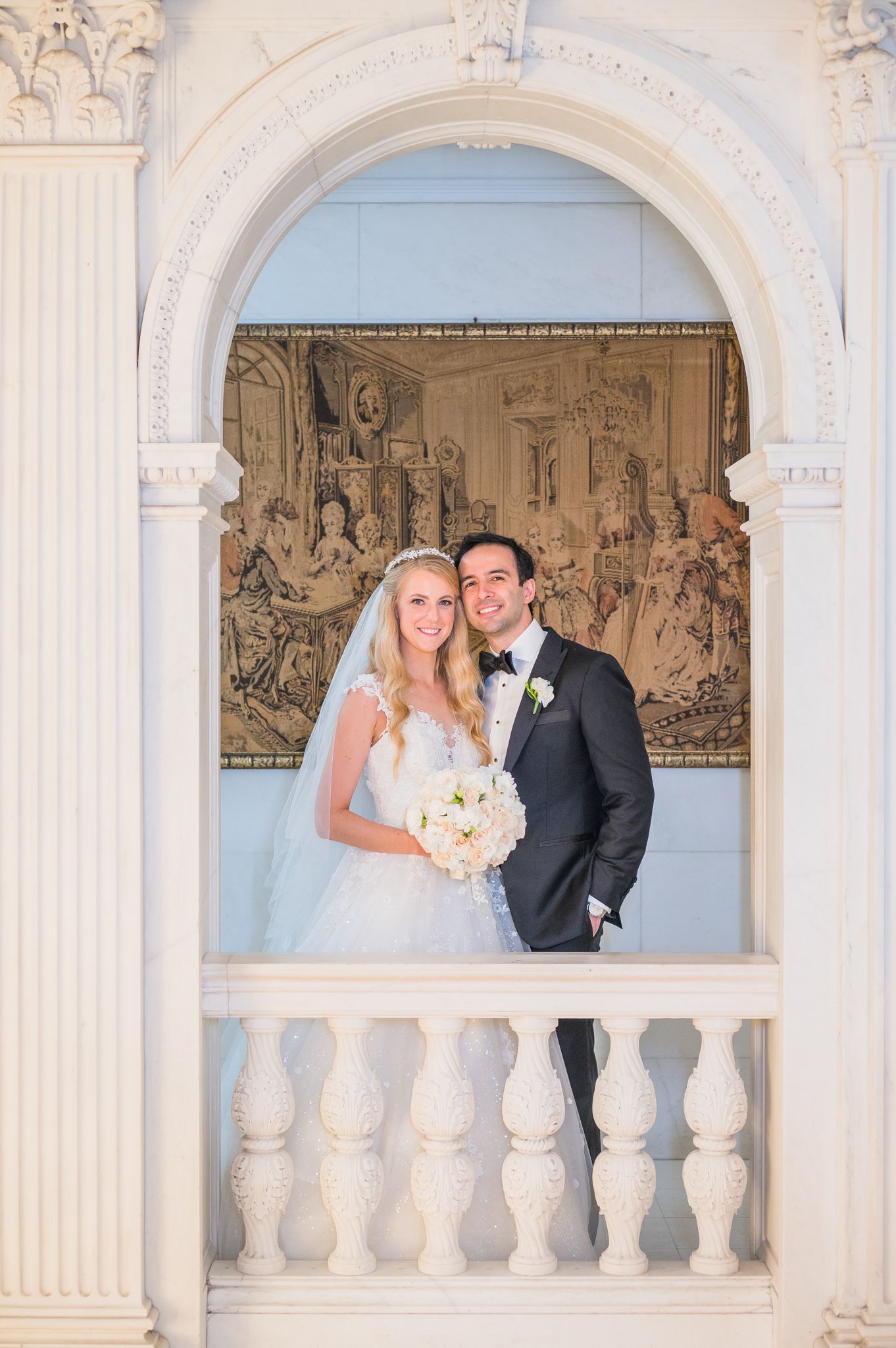 Couple smiling at the camera in the grand hallways of NYIT's interior.