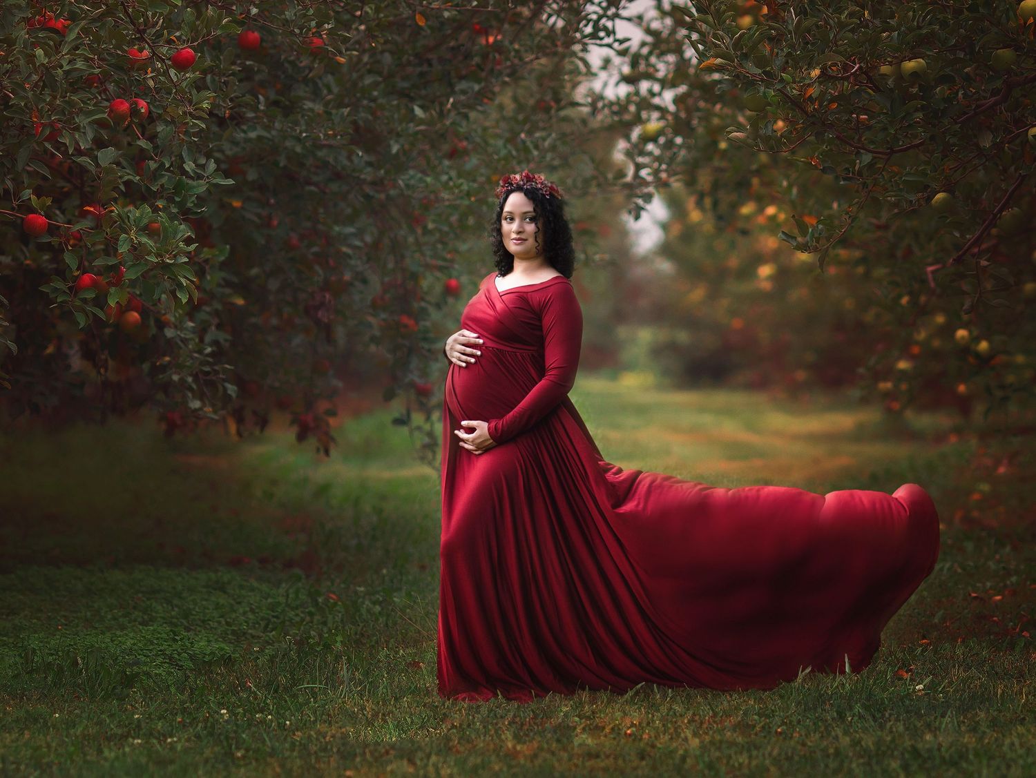 Maternity photo of a flowing red dress in an autumn garden setting with red berries.