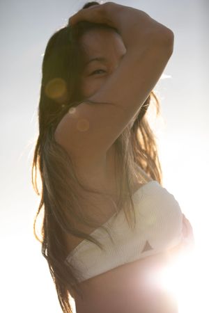 Backlit portrait in white top with sun flare effect.