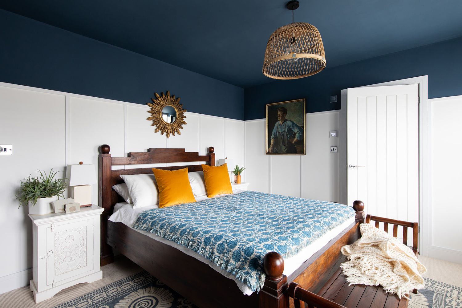 Navy blue bedroom featuring orange accent pillows and patterned bedding creates a bold, contemporary design.