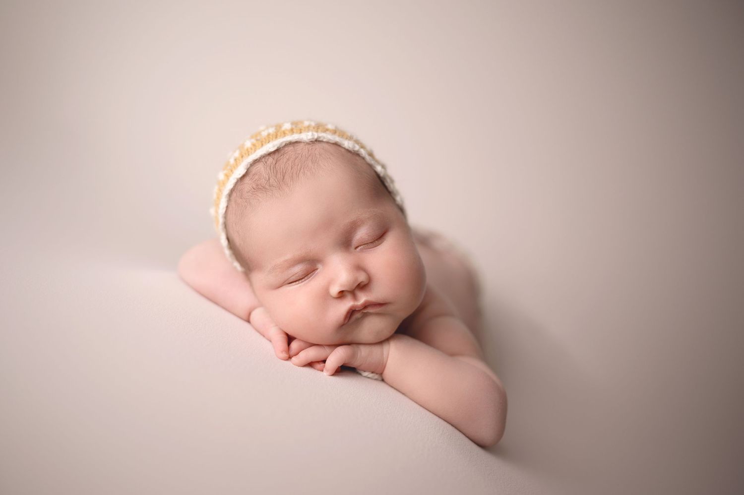 Artistic newborn portraits with delicate lace headband and cream wrapping.