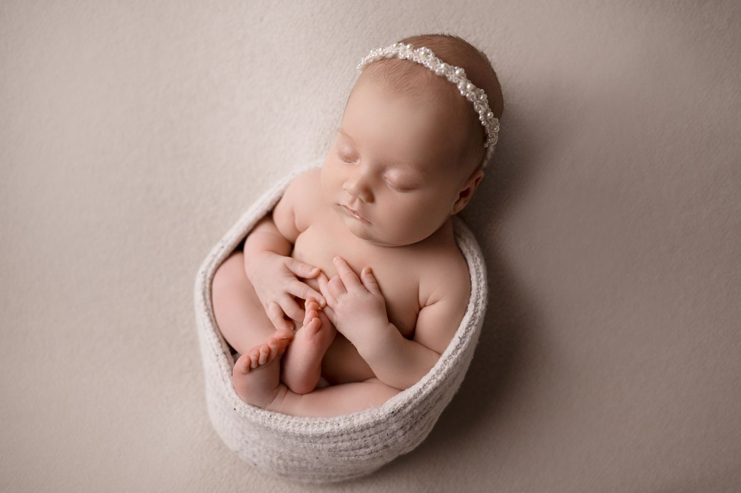 Newborn photography featuring gentle poses in round white basin.