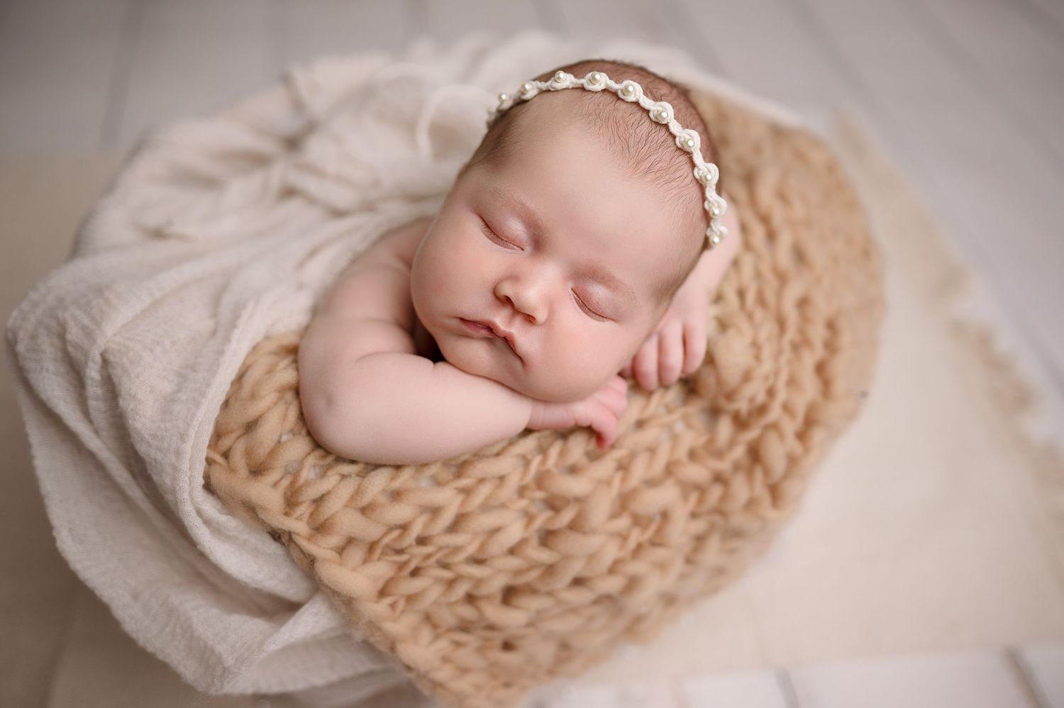 Peaceful newborn portraits on textured cream colored knit blanket.