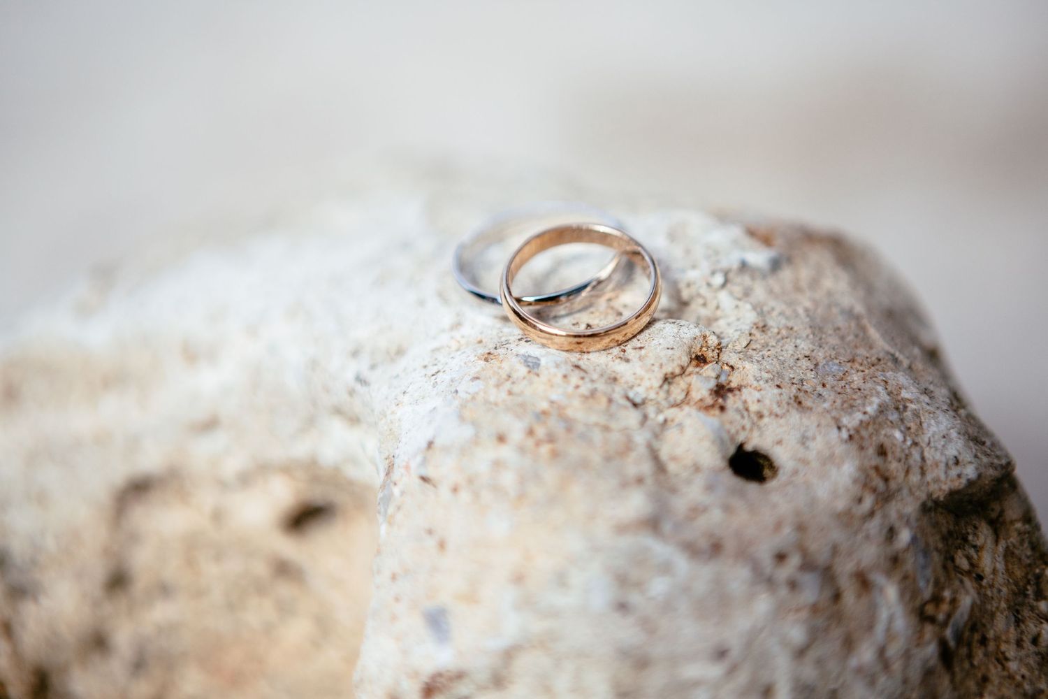 Two wedding rings on a beige stone.