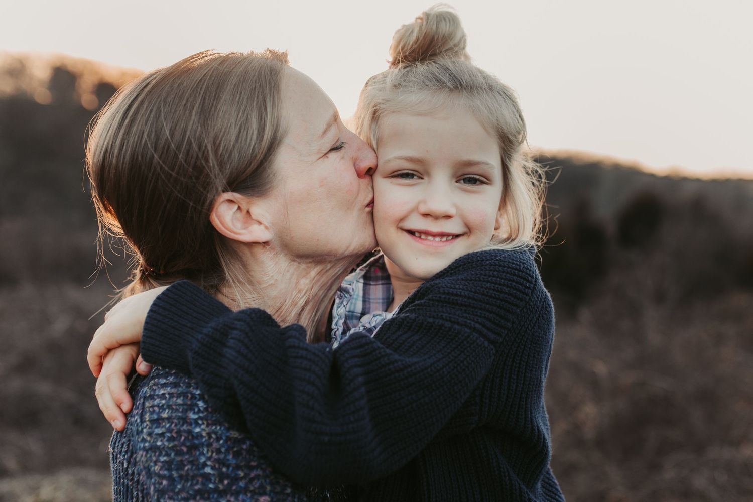 An intimate outdoor portrait of two people sharing an affectionate moment at sunset.
