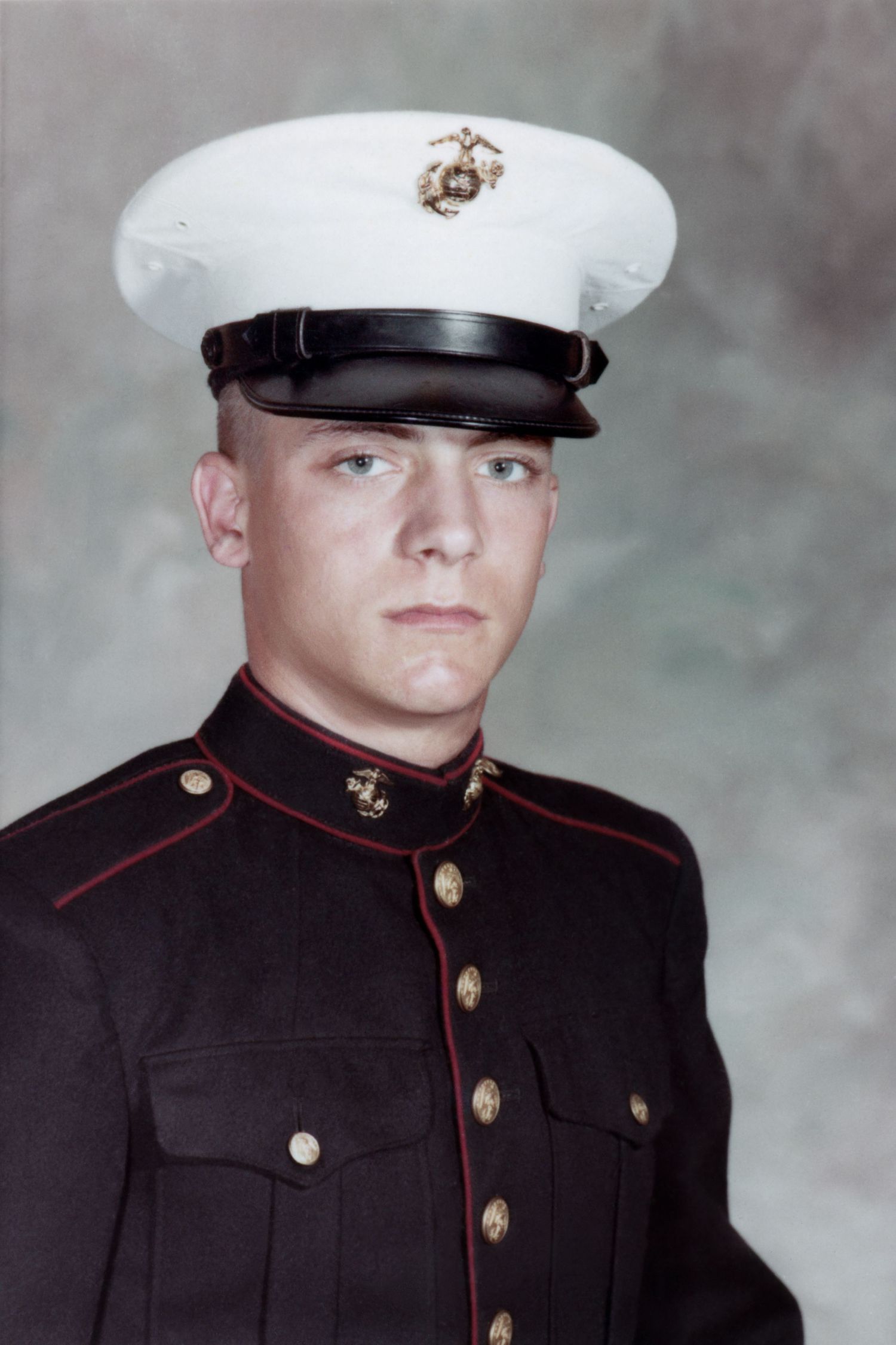 Formal portrait of a US Marine in dress blues and white cap.
