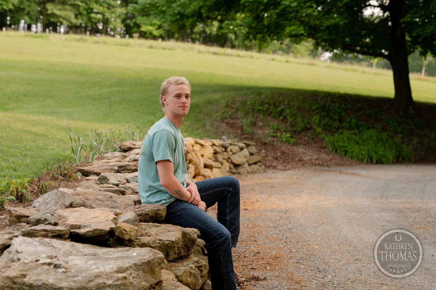 A relaxed outdoor portrait on stone steps with natural landscaping in the background.