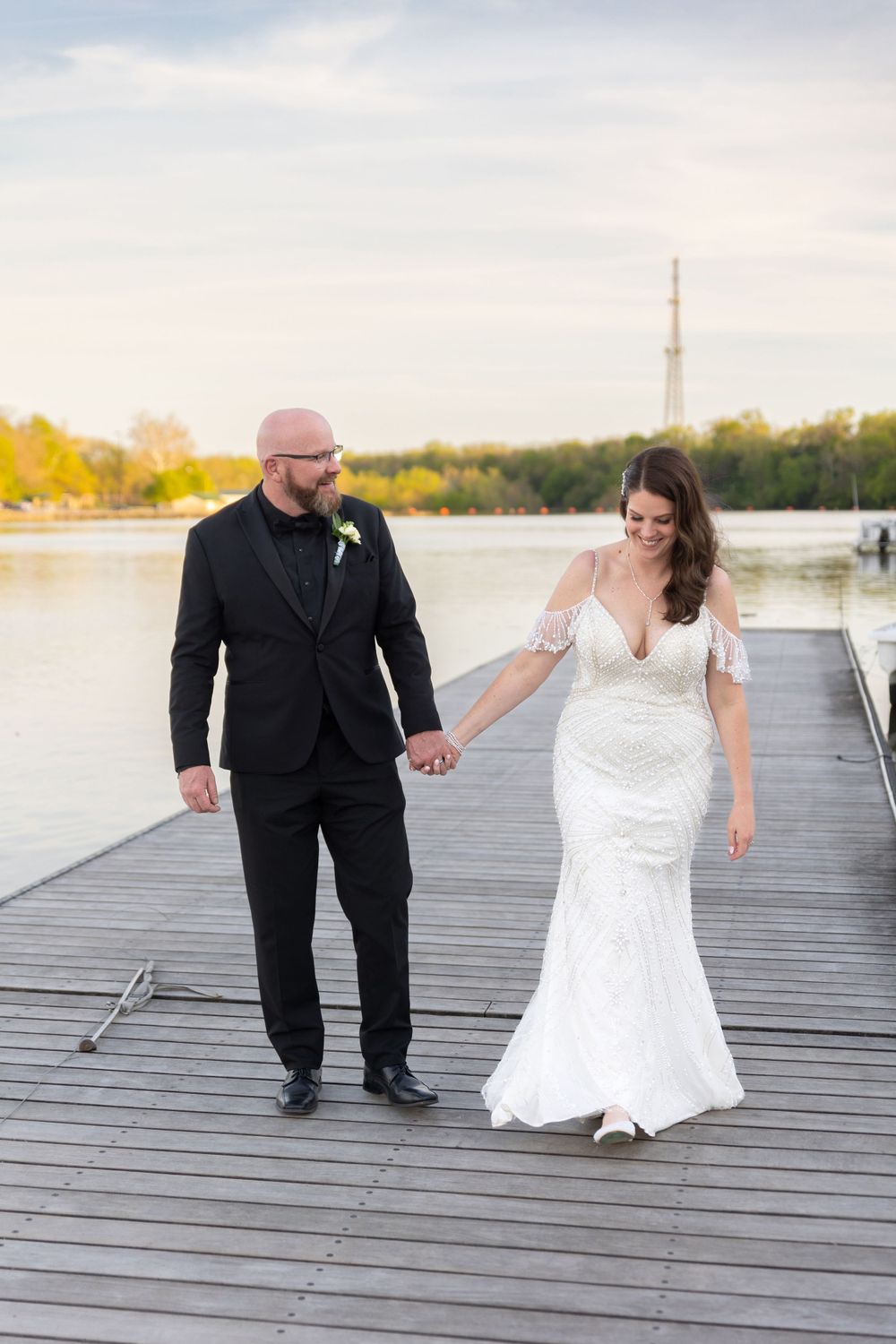 Bride and groom walk hand in hand on boat dock in Dublin Ohio