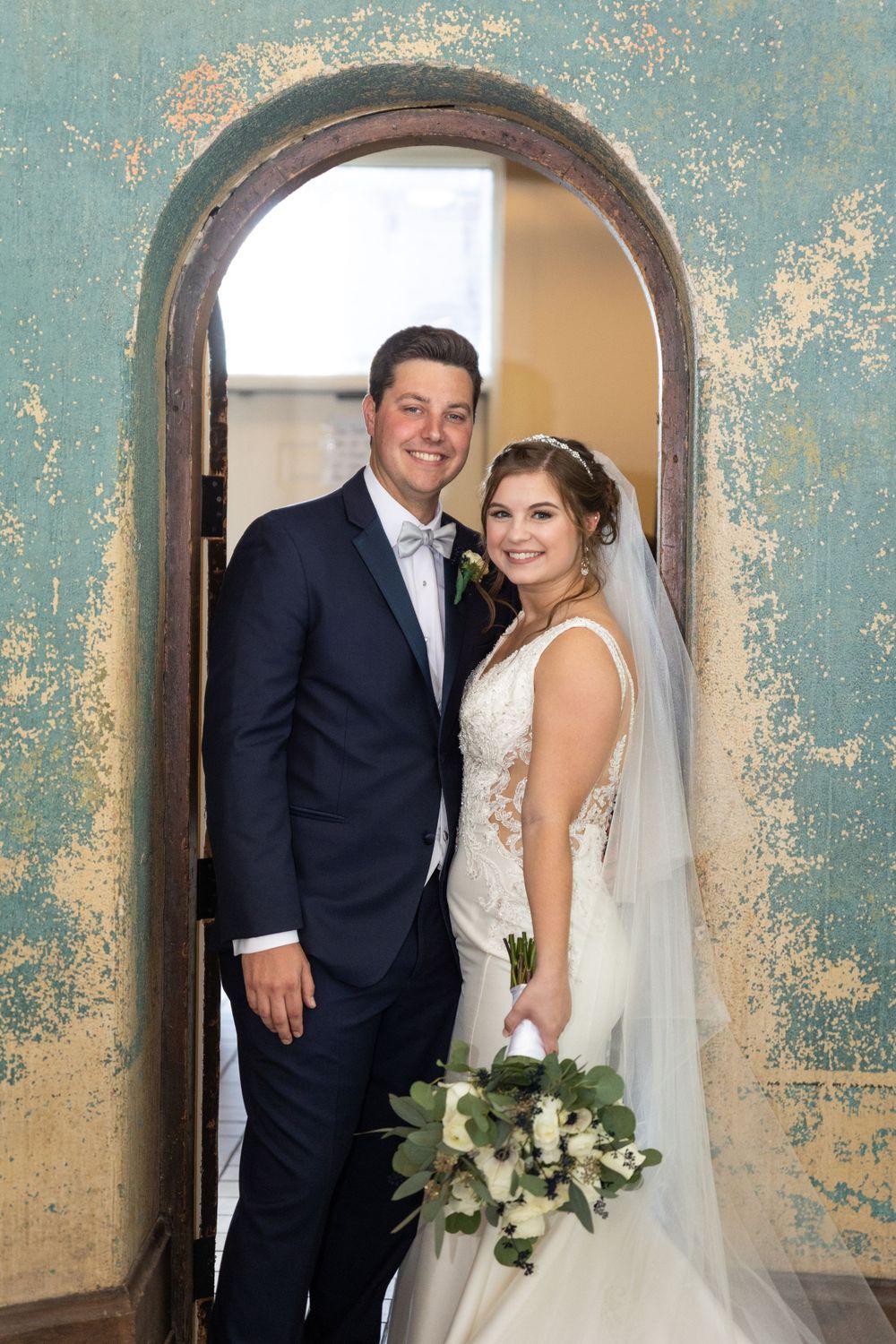 Bride and Groom standing in gorgeous archway at their wedding reception at  The Monastery Event Center