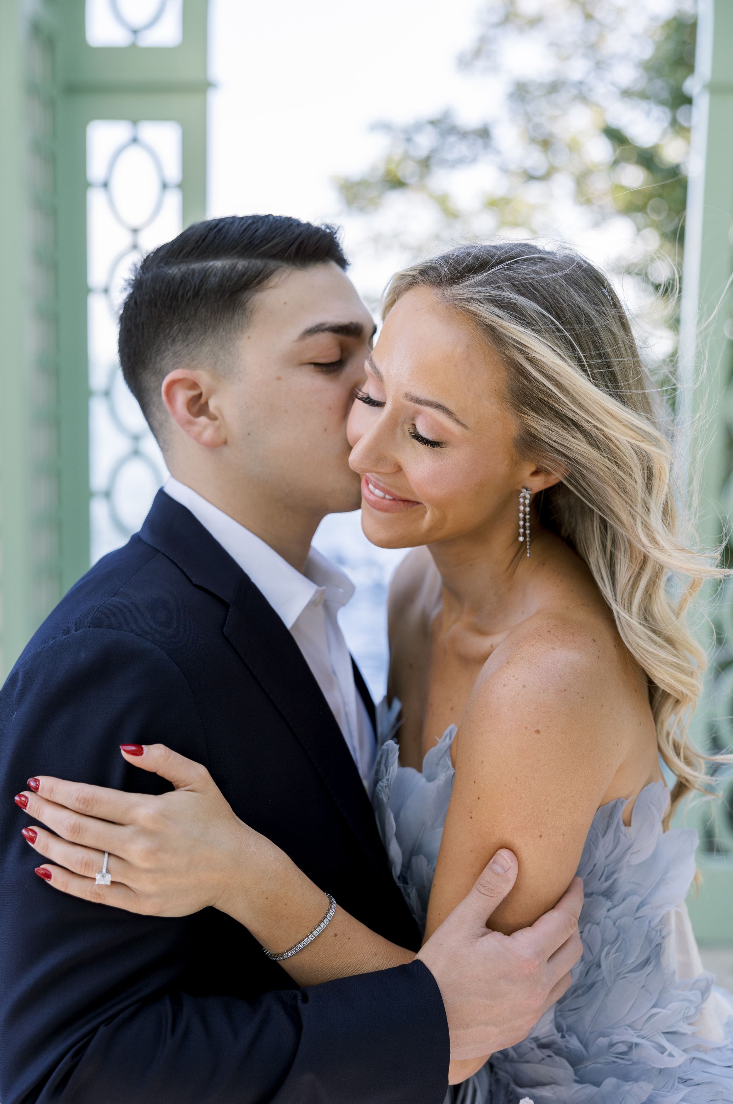 An intimate moment captured between a couple in formal wear beneath a mint green pavilion.