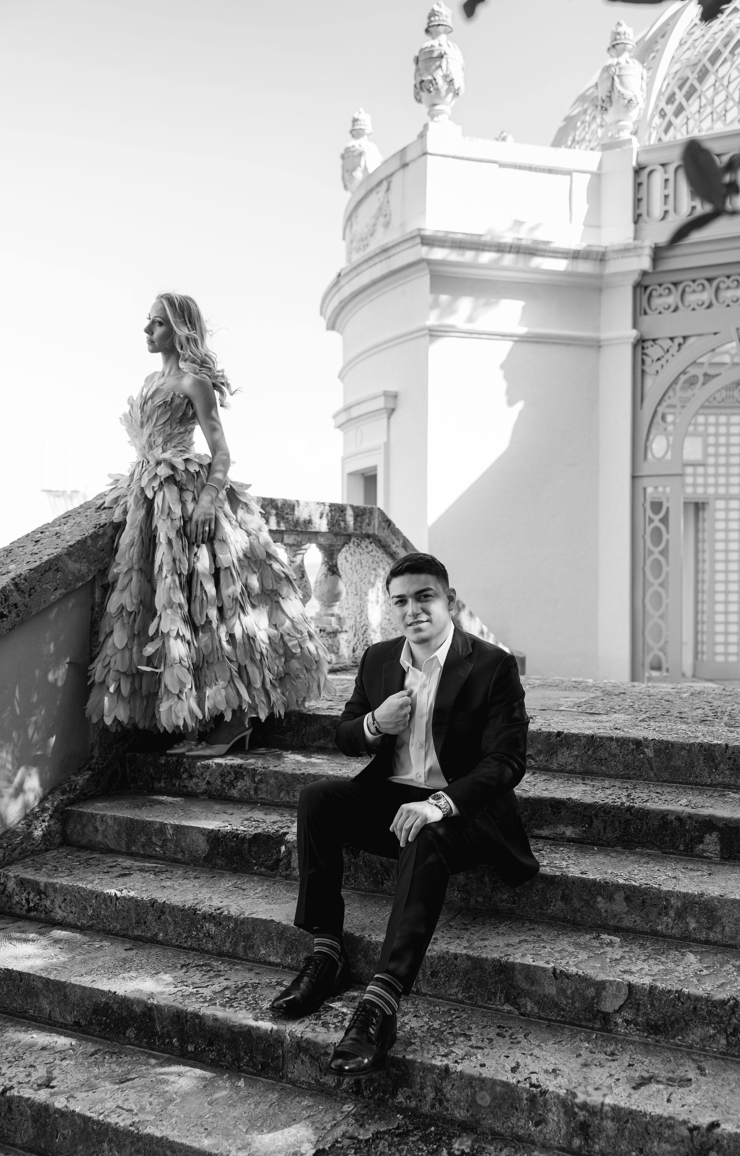 A black and white photo of a couple at an ornate historic pavilion with stone steps.
